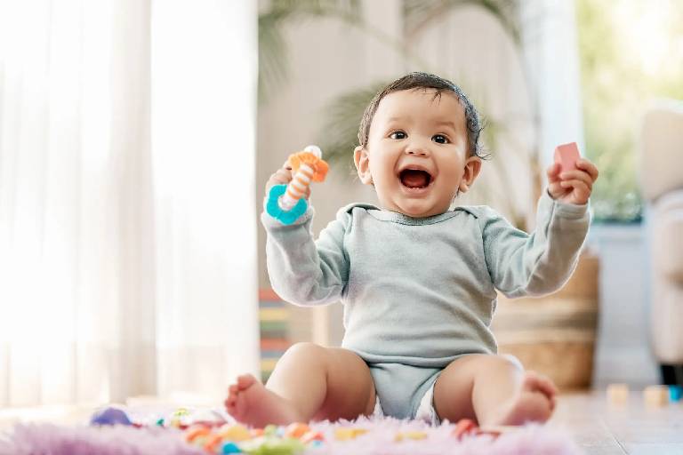 A joyful baby sitting and playing with toys.