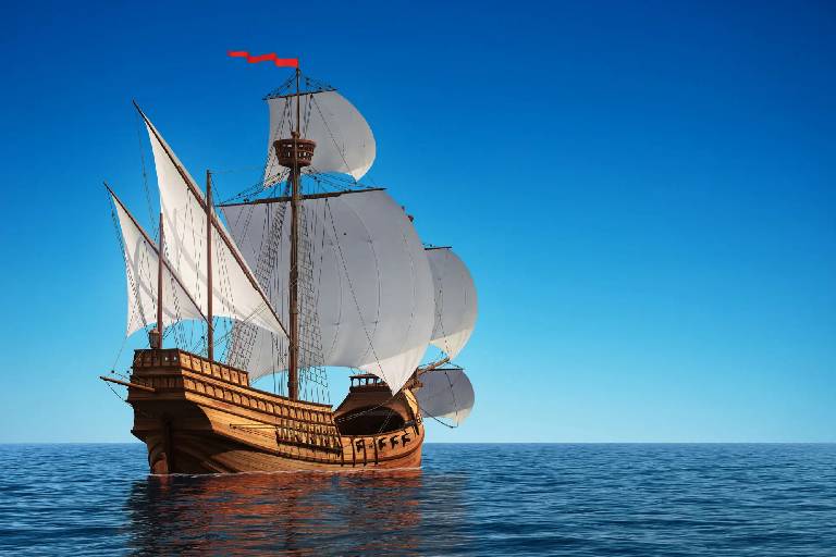 A classic wooden ship with sails on a calm sea under clear blue skies.
